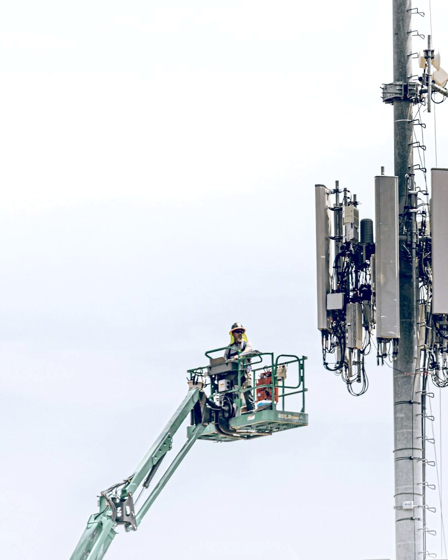 A technician on a lift working on a telecom tower