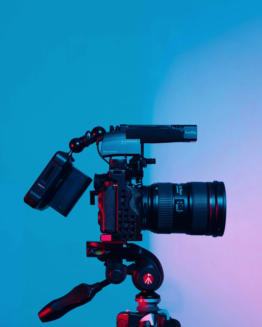 A cinema camera on a tripod against a blue backdrop