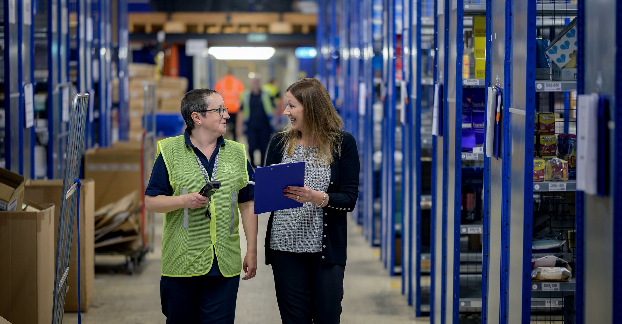Two colleagues walking through a warehouse aisle
